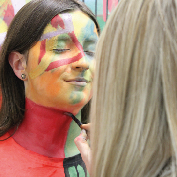 Student getting her face painted by and art and design student